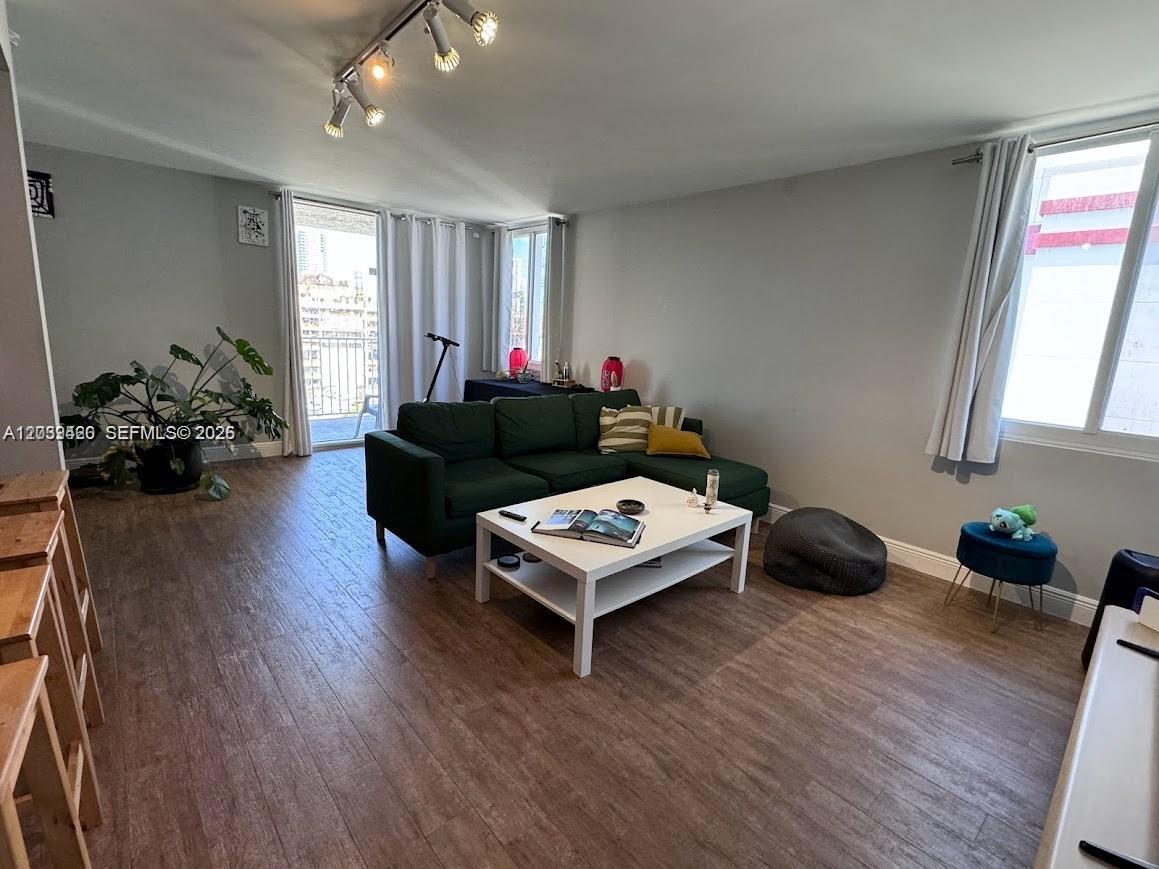 A living room features a dark green sectional sofa, a white coffee table, and wood-look flooring — 800 N Miami Ave # 1008, Miami FL 33136, MIAMI, FL