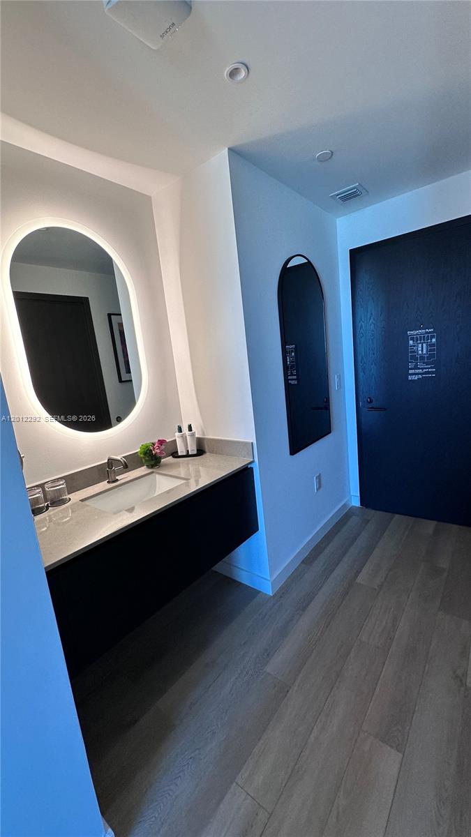 A modern bathroom features a floating vanity, an oval backlit mirror, and light wood flooring — 20 NE 11 # 2212A, Miami FL 33132, MIAMI, FL