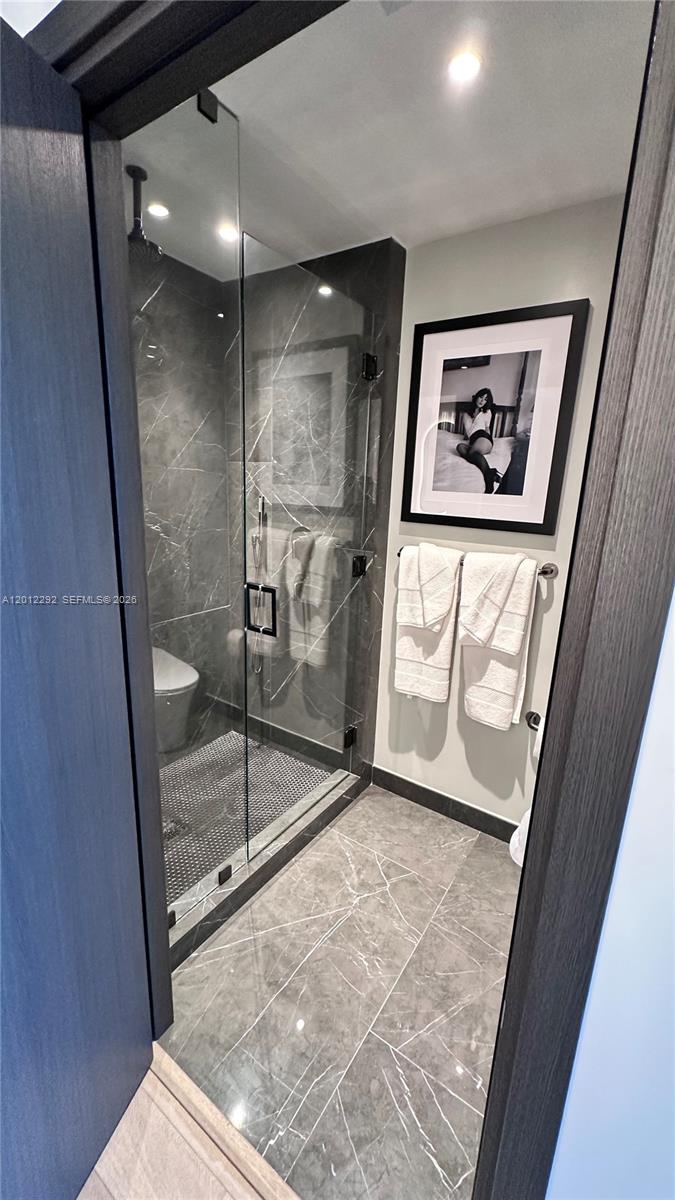 A modern bathroom features a glass-enclosed shower with marble-patterned tile and dark wood trim — 20 NE 11 # 2212A, Miami FL 33132, MIAMI, FL