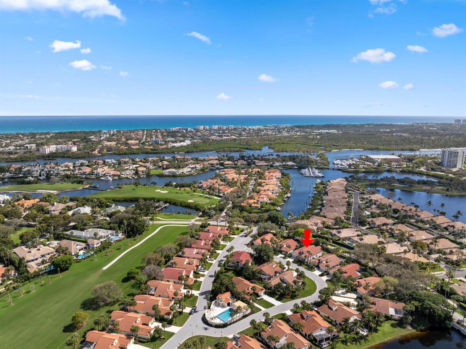 An aerial view shows a residential neighborhood with houses, a golf course, and a waterway — 16613 Hidden Cove Drive, Jupiter FL 33477, JUPITER, FL