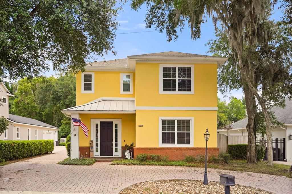 A two-story yellow house with a brick base, a front porch, and a paved driveway — 161 VINE STREET, OVIEDO, FL