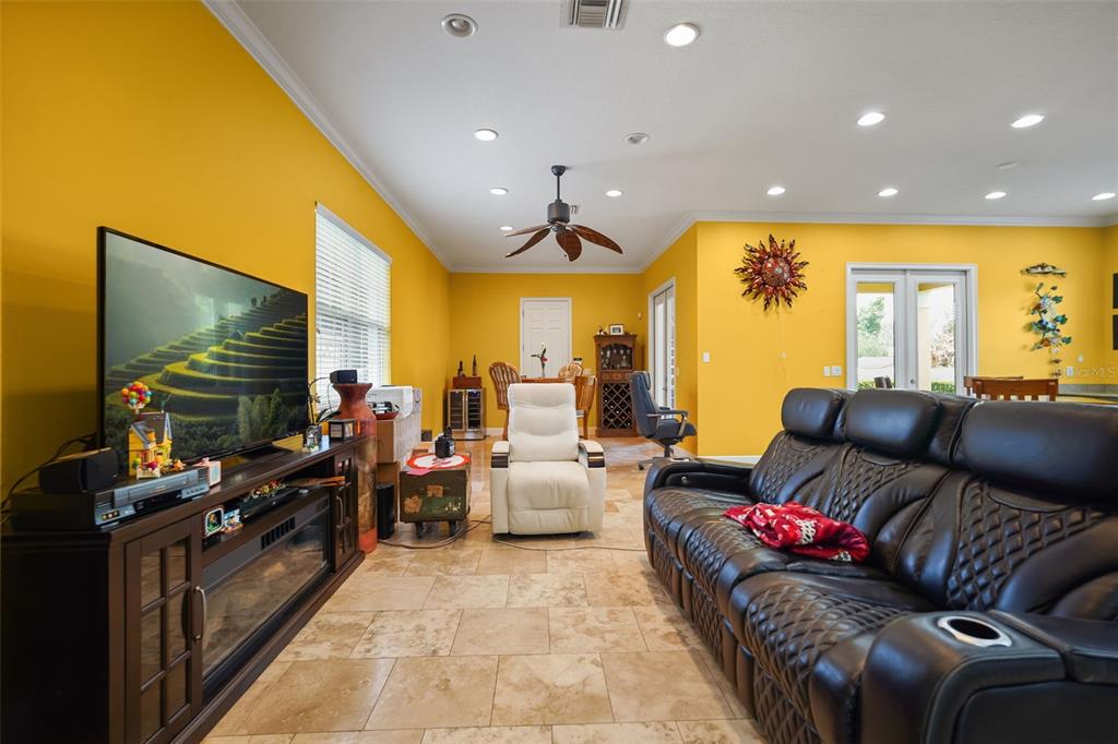 A living room features yellow walls, tile flooring, a black leather sofa, and a television — 161 VINE STREET, OVIEDO, FL