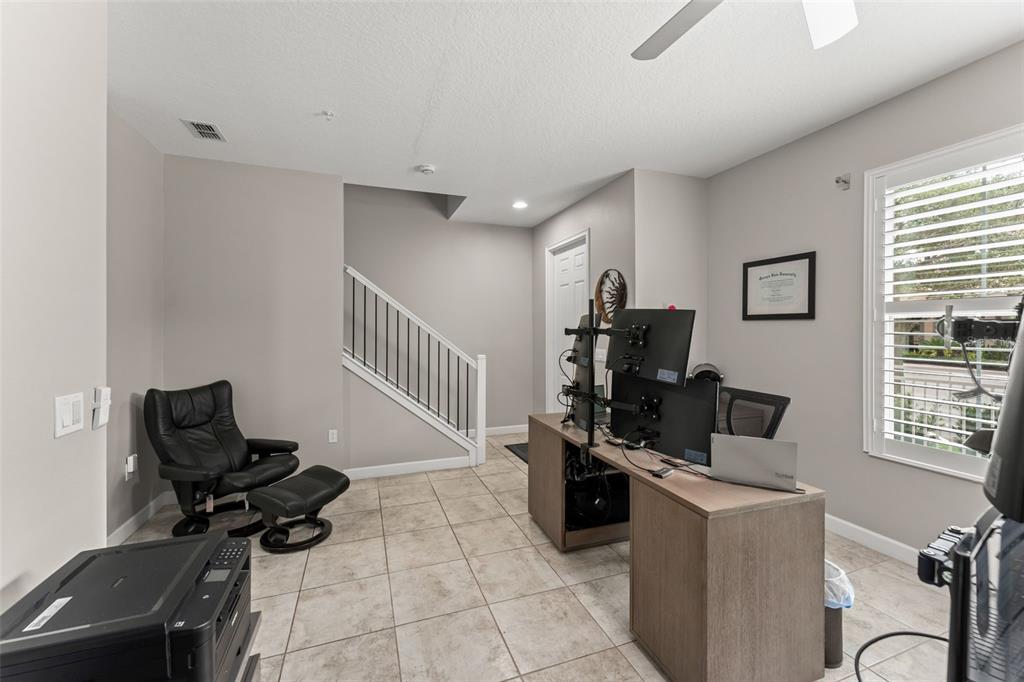 A home office features tile flooring, a desk with multiple monitors, and a staircase — 1457 LAKE GEORGE DRIVE UNIT 1457, LAKE MARY, FL