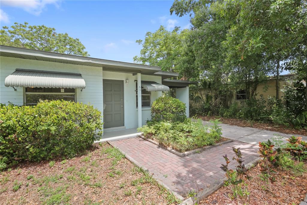 A white house with a brick walkway, metal awnings, and a gray front door — 6311 37TH AVENUE N, ST PETERSBURG, FL