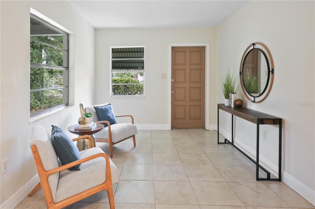 A bright entryway features light tile floors, two armchairs, a console table, and a brown door — 6311 37TH AVENUE N, ST PETERSBURG, FL