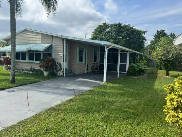 A single-story house with light siding, a concrete driveway, and a covered carport — 6059 Palm Harbour Drive, Atlantis FL 33462, ATLANTIS, FL