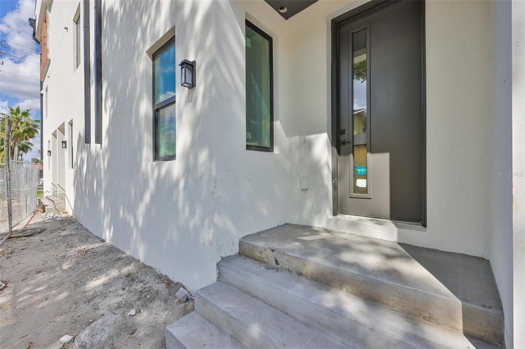 A modern white exterior wall features a dark gray front door and concrete steps — 310 W COLUMBUS DRIVE UNIT 2, TAMPA, FL
