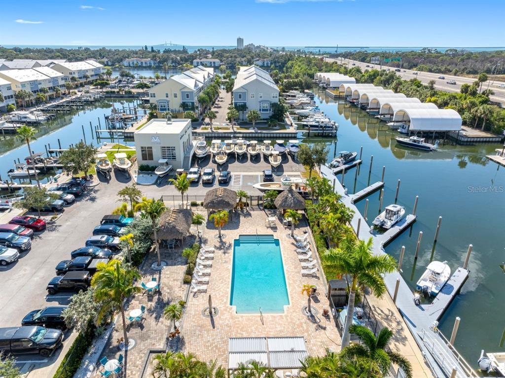 An aerial view shows a swimming pool, parking lot, and boat slips at a waterfront complex — 6057 MOORINGS DRIVE S, ST PETERSBURG, FL