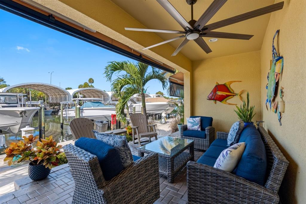 A covered patio features wicker furniture, a ceiling fan, and a view of docked boats — 6057 MOORINGS DRIVE S, ST PETERSBURG, FL