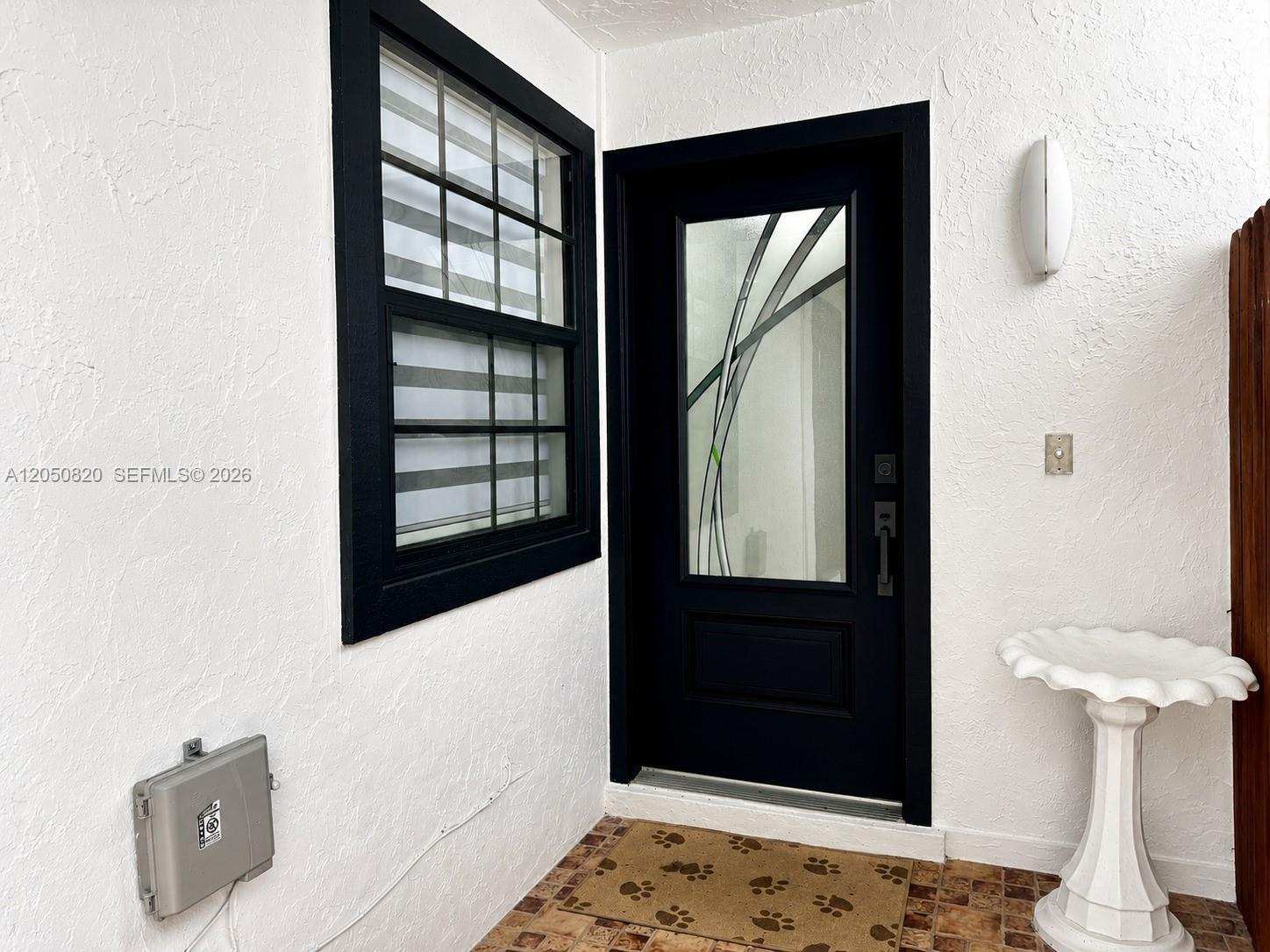 A black-framed door and window are set against a white stucco wall on a porch — 10626 SW 148th Ave Dr, Miami FL 33196, MIAMI, FL