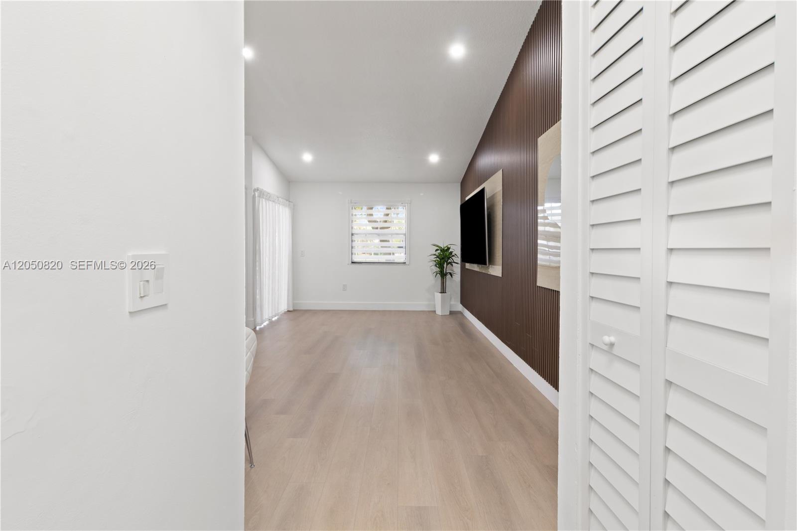 A living room features light wood flooring, a slatted wood accent wall, and recessed lighting — 10626 SW 148th Ave Dr, Miami FL 33196, MIAMI, FL