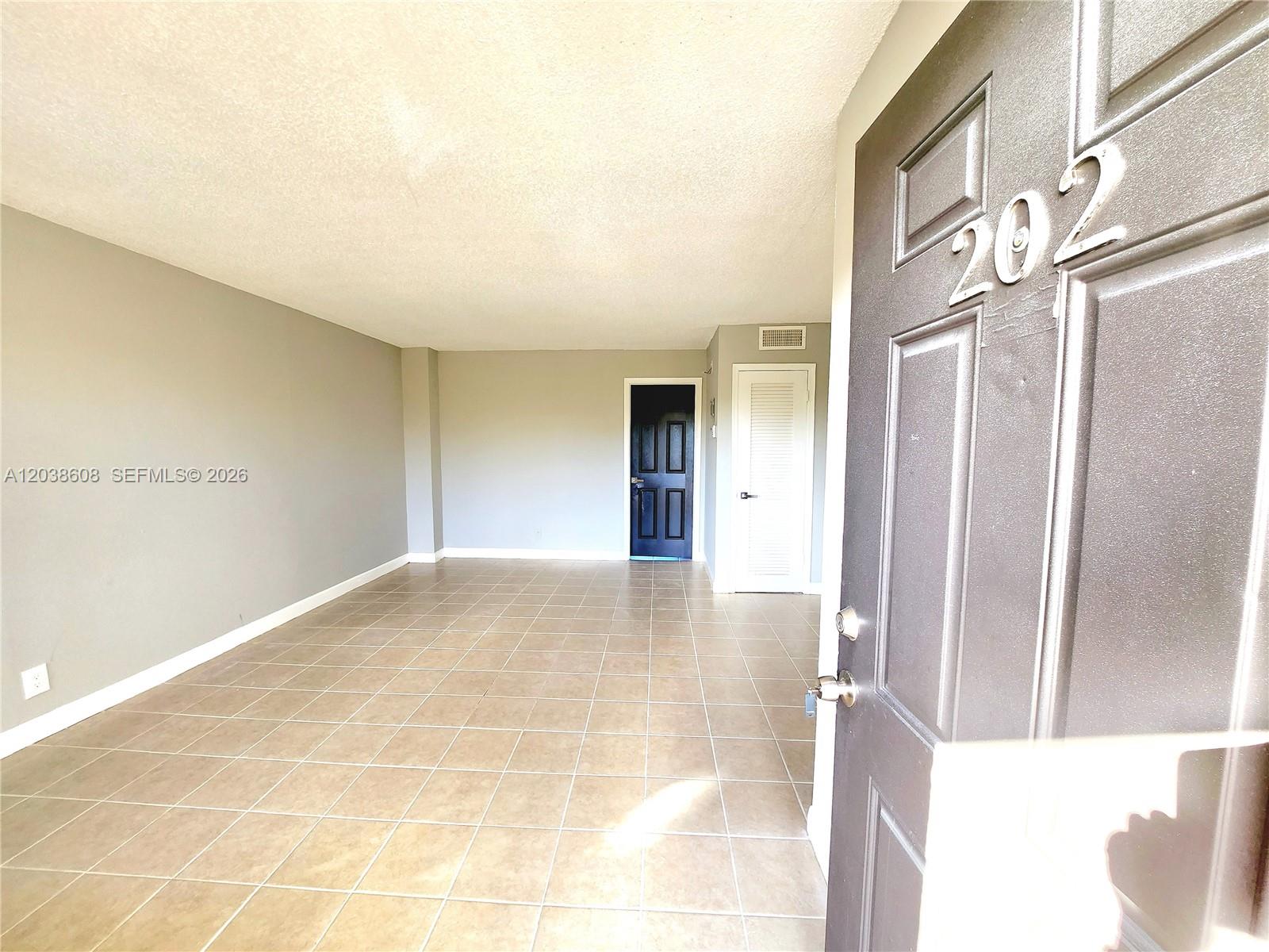 An interior view shows a room with tiled floors, gray walls, and two closed doors — 191 SW 15th St # 202, Pompano Beach FL 33060, POMPANO BEACH, FL