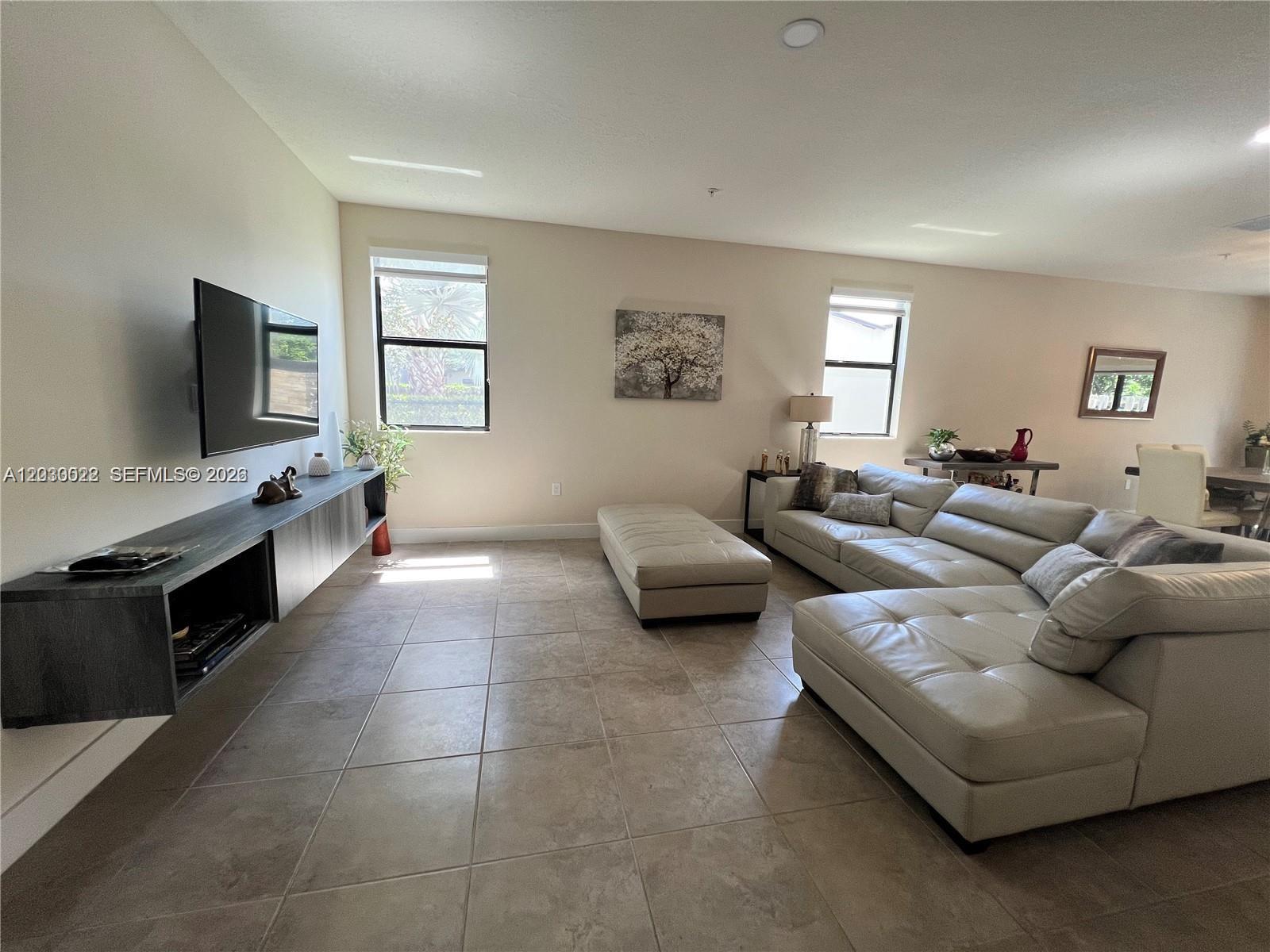A living room features a large sectional sofa, a floating media console, and tile flooring — 10455 NW 82nd St # 1, Doral FL 33178, DORAL, FL