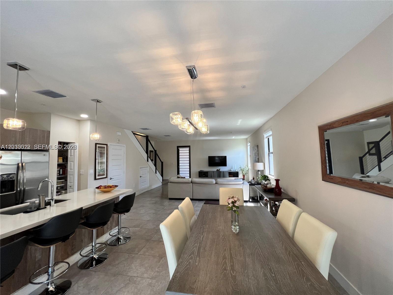 An open-concept living area features a kitchen with a breakfast bar and a dining space — 10455 NW 82nd St # 1, Doral FL 33178, DORAL, FL