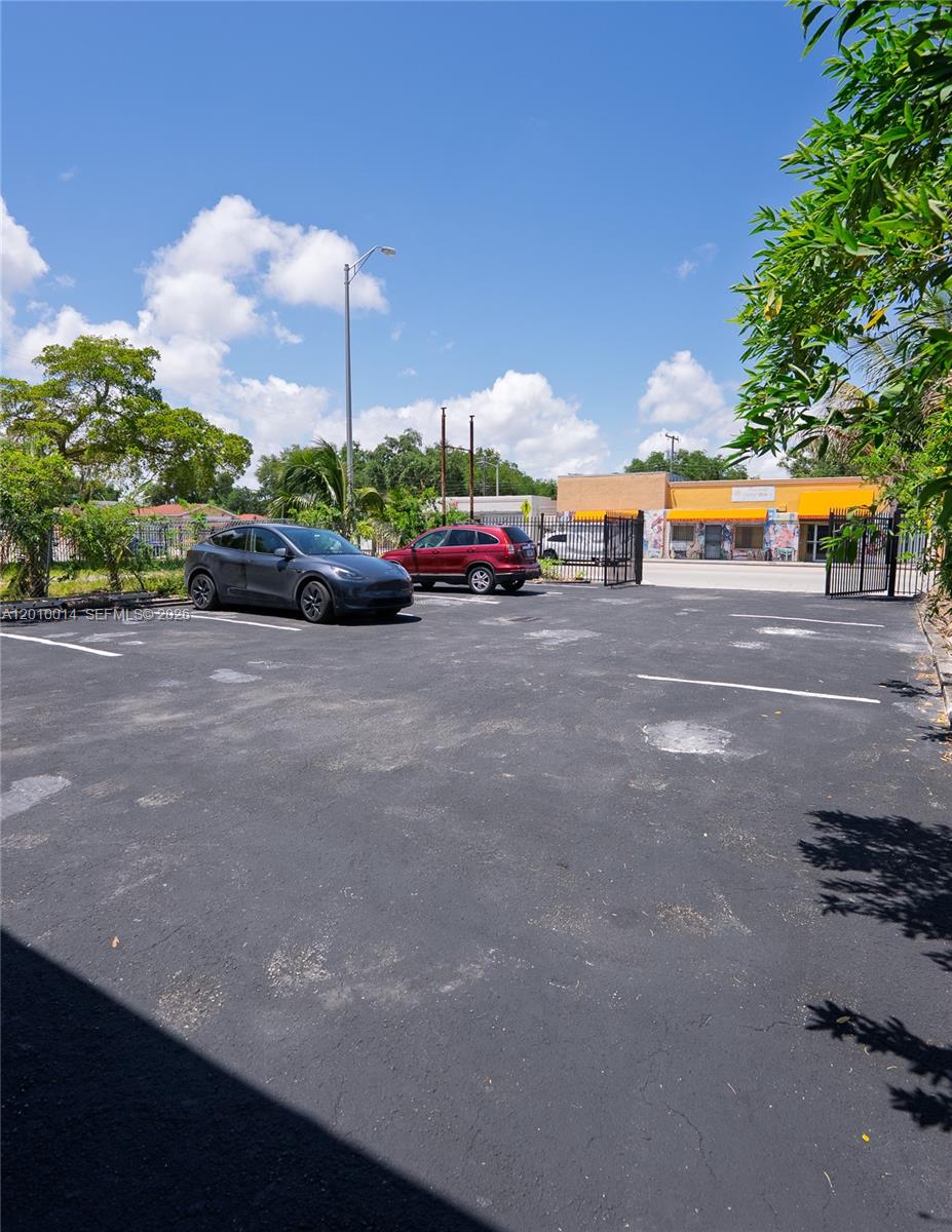 An outdoor parking lot features two parked cars and a gated entrance to a building — 88 NW 54th St, Miami FL 33127, MIAMI, FL