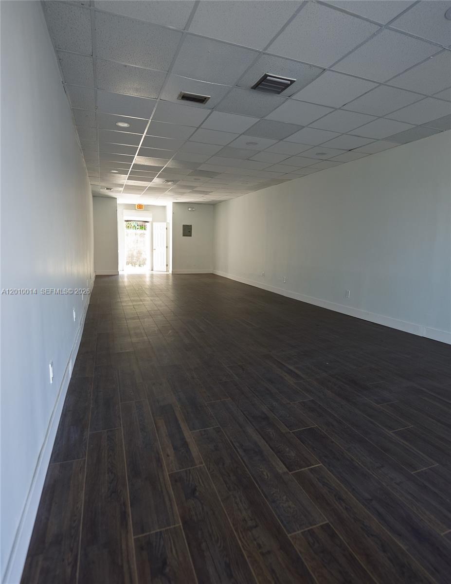 An empty commercial space features dark wood-look flooring, white walls, and a drop ceiling — 88 NW 54th St, Miami FL 33127, MIAMI, FL