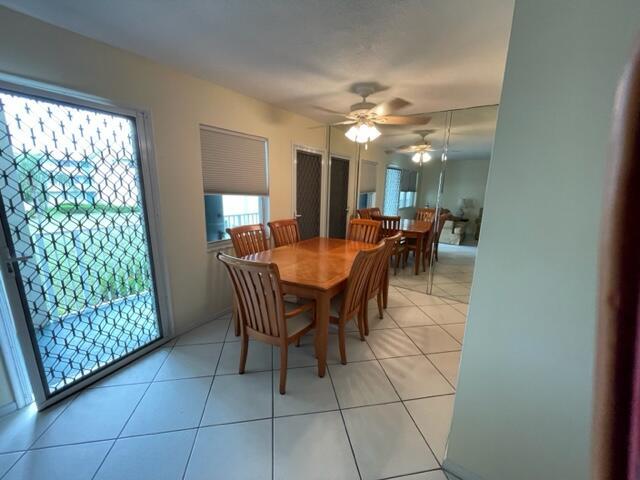 A dining room with a wooden table, six chairs, tiled floors, and mirrored wall panels — 350 Horizons E # 206, Boynton Beach FL 33435, BOYNTON BEACH, FL