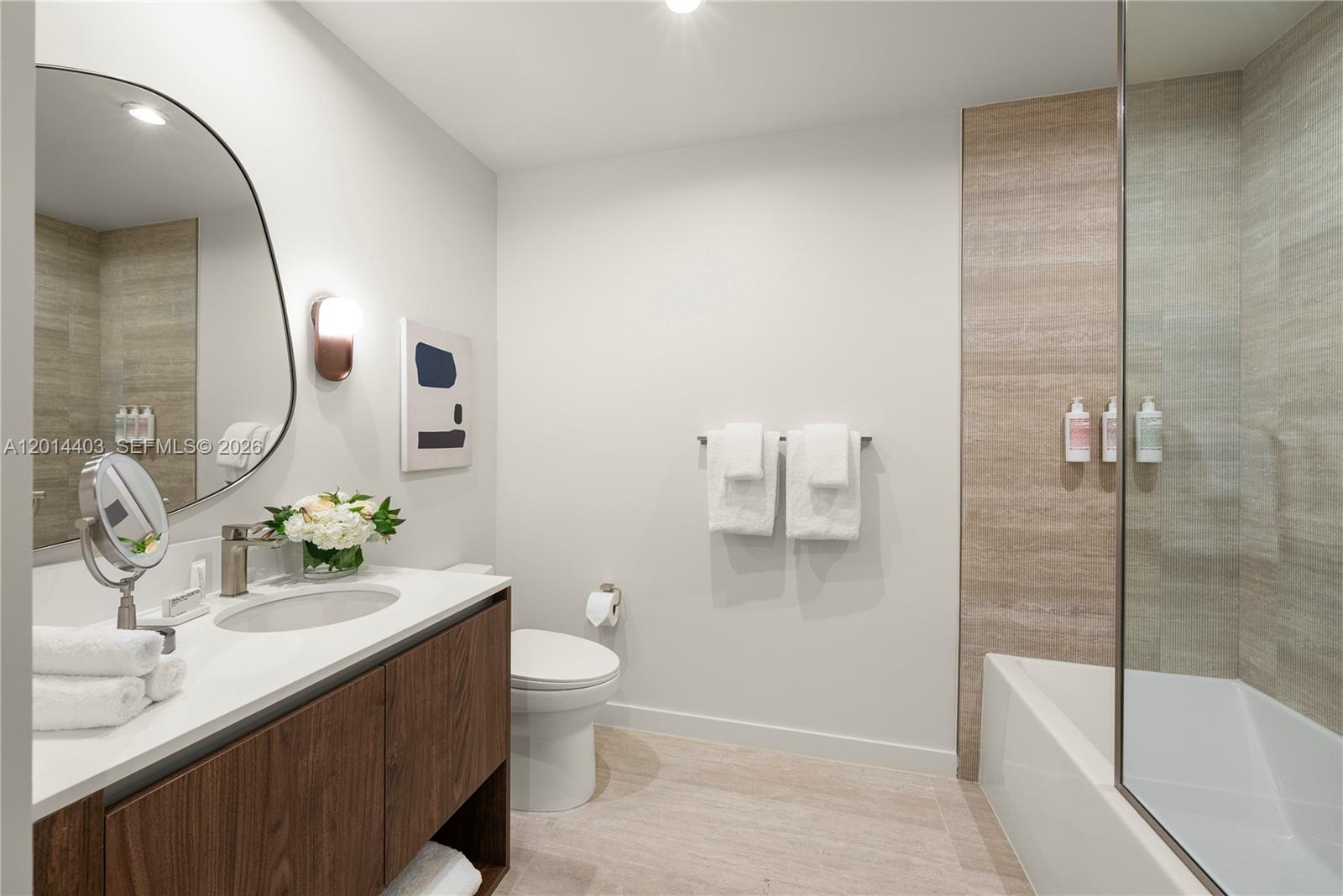 A modern bathroom features a wood vanity, a round mirror, and a tiled shower area — 1611 SW 2nd Ave # 314, Miami FL 33129, MIAMI, FL