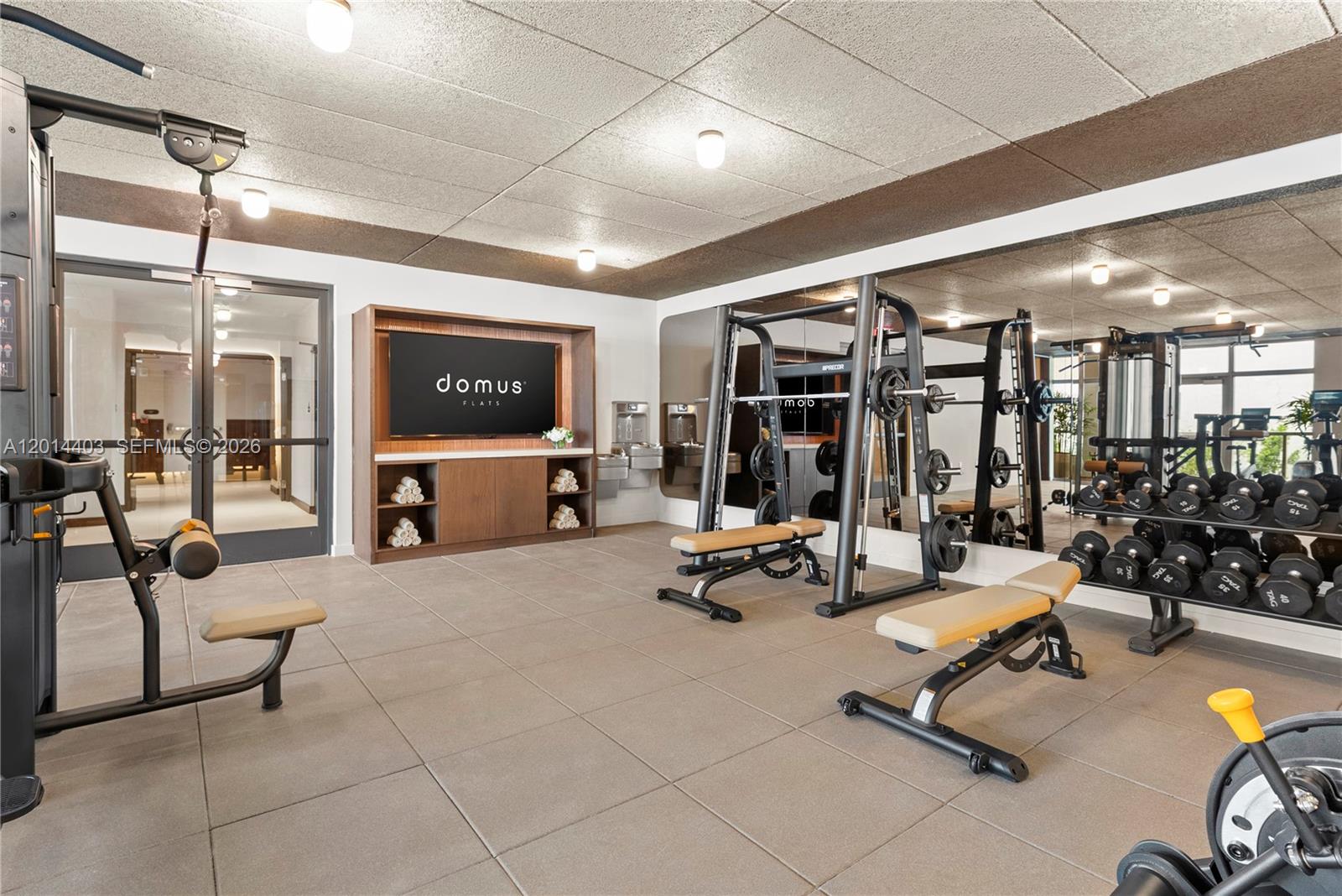 A fitness center features a television, a weight rack, benches, and a mirrored wall — 1611 SW 2nd Ave # 314, Miami FL 33129, MIAMI, FL