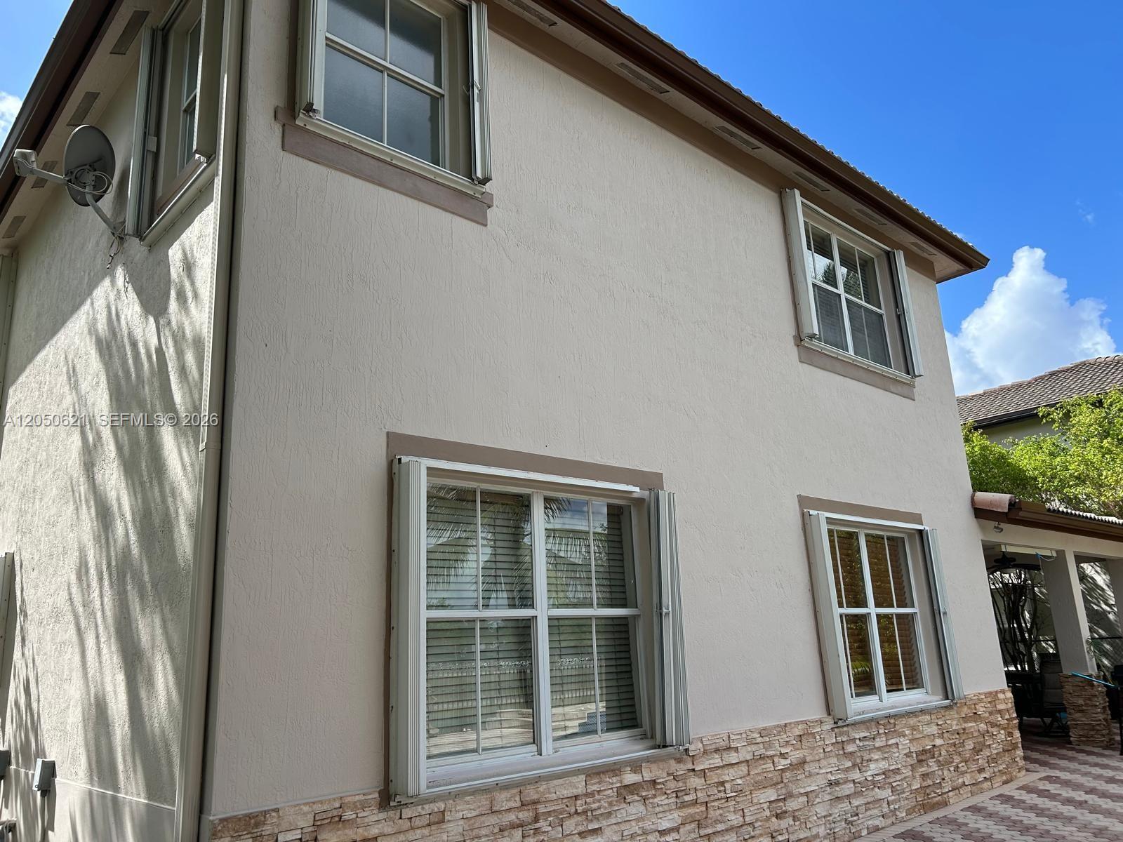 The exterior of a two-story stucco house features stone veneer siding and window shutters — 1331 SW 153rd Path, Miami FL 33194, MIAMI, FL