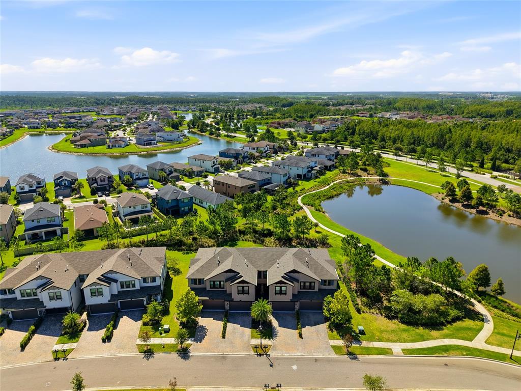 An aerial view shows a suburban neighborhood with townhomes, single-family houses, and two ponds — 4540 ALMADA LANE, WESLEY CHAPEL, FL