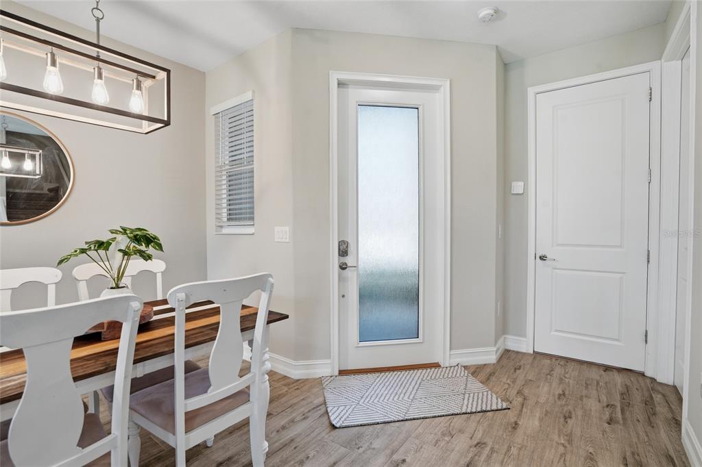 A dining area features a wooden table, white chairs, a pendant light, and a glass door — 4540 ALMADA LANE, WESLEY CHAPEL, FL
