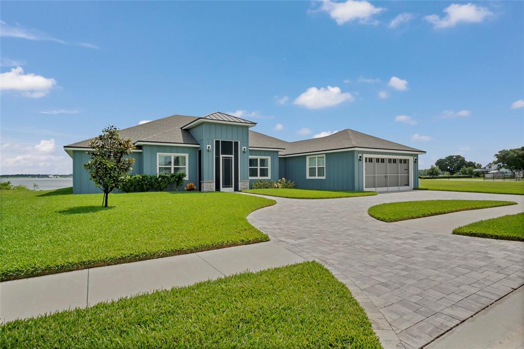 A blue single-story house with a paved driveway and a large green lawn — 1153 ENCLAVE COURT, AUBURNDALE, FL
