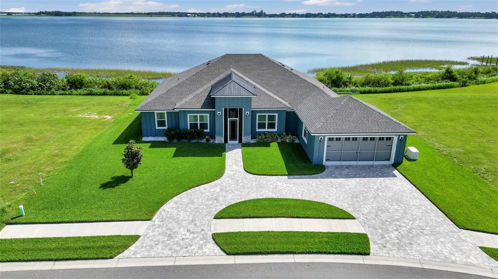 An aerial view of a blue single-story house with a paved driveway facing a lake — 1153 ENCLAVE COURT, AUBURNDALE, FL