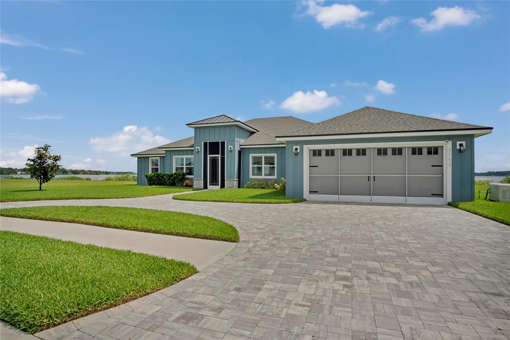 A blue single-story house with a large paver driveway and a three-car garage — 1153 ENCLAVE COURT, AUBURNDALE, FL
