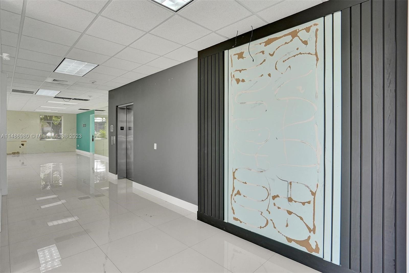 An office hallway features a tiled floor, a gray accent wall, and a decorative panel — 15620 SW 29th St, Miramar FL 33027, MIRAMAR, FL