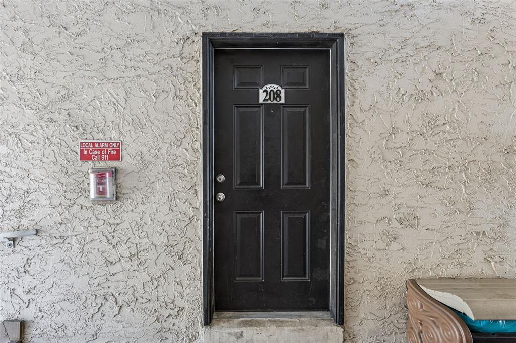 A black door labeled 208 is set into a textured, light-colored exterior wall — 145 N PEARL LAKE CSWY UNIT 208, ALTAMONTE SPRINGS, FL