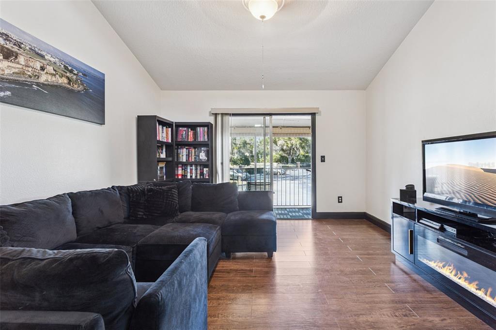 A living room features a dark sectional sofa, a bookshelf, and a fireplace media console — 145 N PEARL LAKE CSWY UNIT 208, ALTAMONTE SPRINGS, FL
