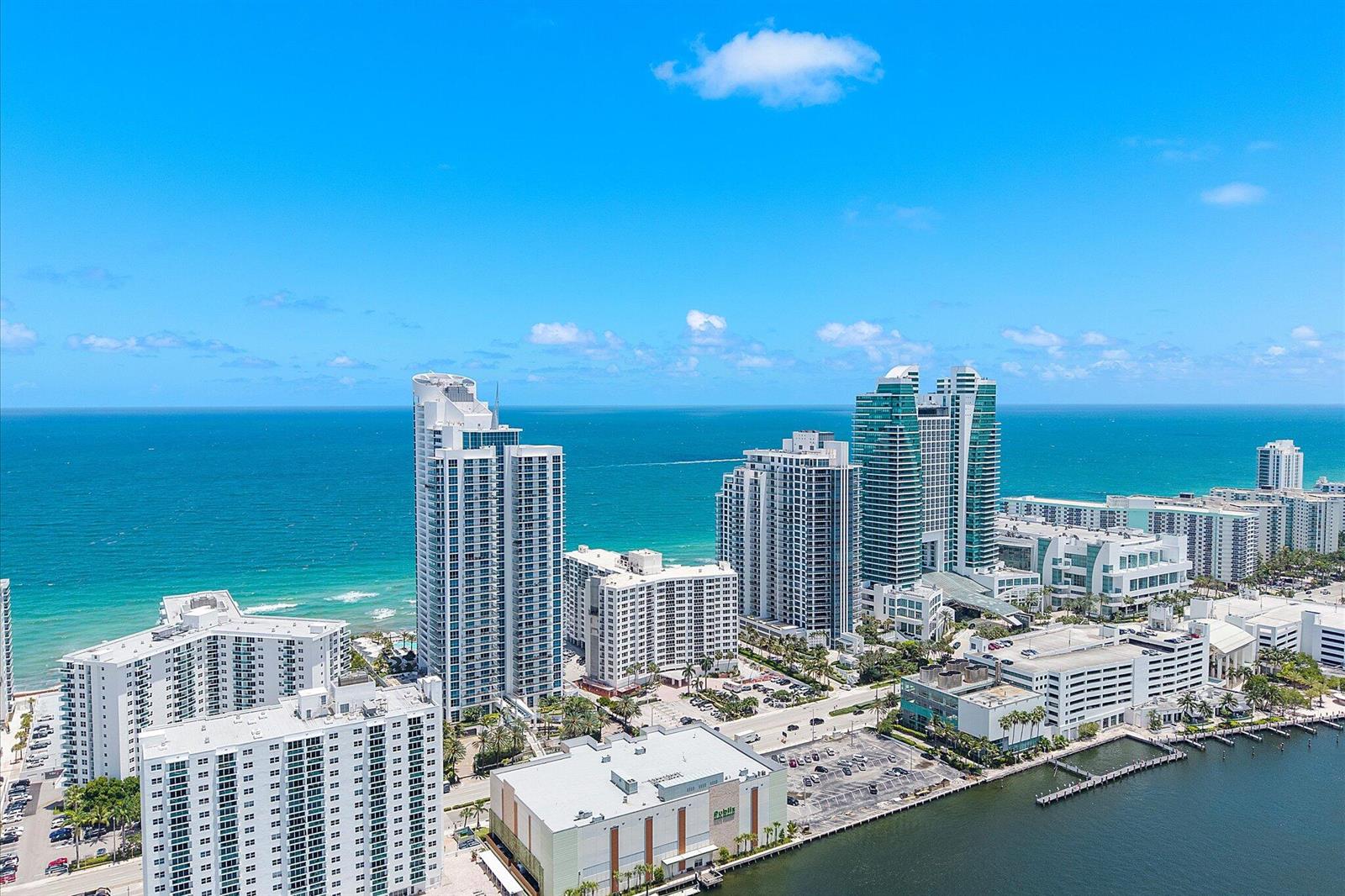 An aerial view shows high-rise residential buildings along a coastline next to a waterway — 3101 S Ocean Drive # 2707, Hollywood FL 33019, HOLLYWOOD, FL