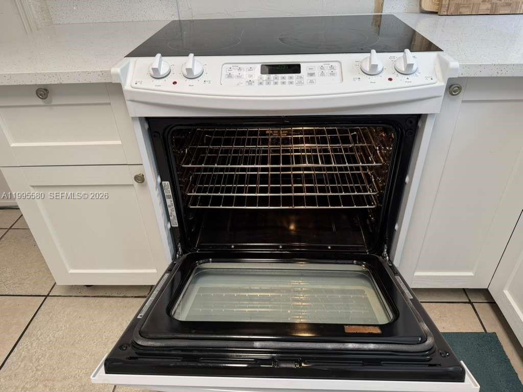 A white electric range with a glass cooktop is installed between white kitchen cabinets — 3 SW 7th Ave, Dania Beach FL 33004, DANIA BEACH, FL