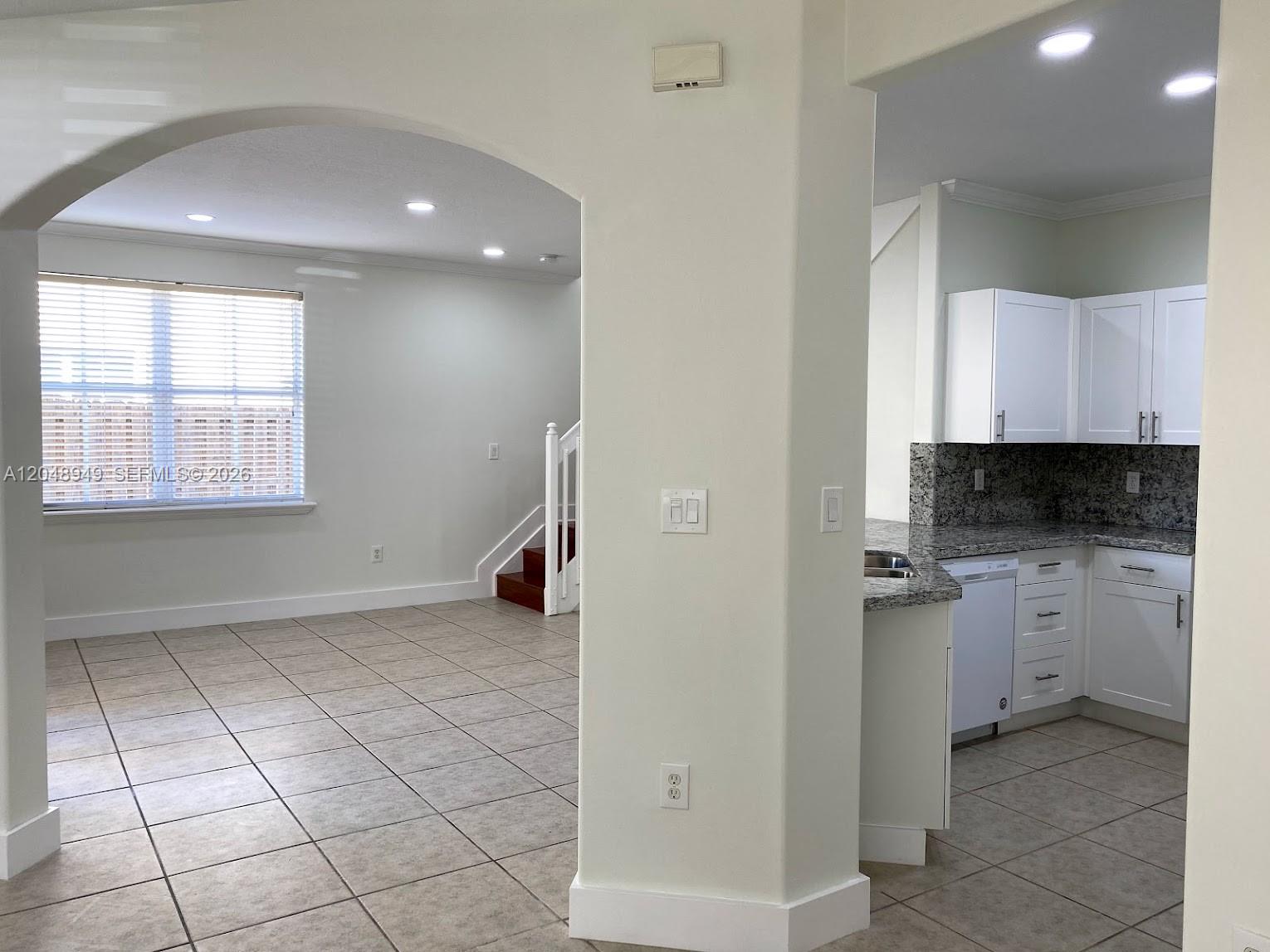 A view through an arched doorway shows a tiled living area and a white kitchen — 4874 NW 107th Path, Doral FL 33178, DORAL, FL