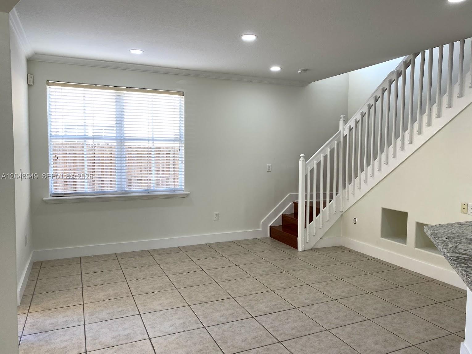 A room with tiled floors, a window with blinds, and a staircase with white railings — 4874 NW 107th Path, Doral FL 33178, DORAL, FL