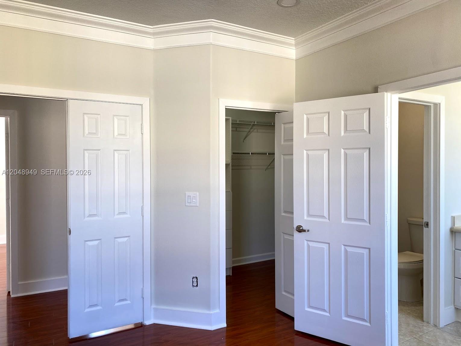 A room with hardwood floors, crown molding, two white doors, and an open walk-in closet — 4874 NW 107th Path, Doral FL 33178, DORAL, FL