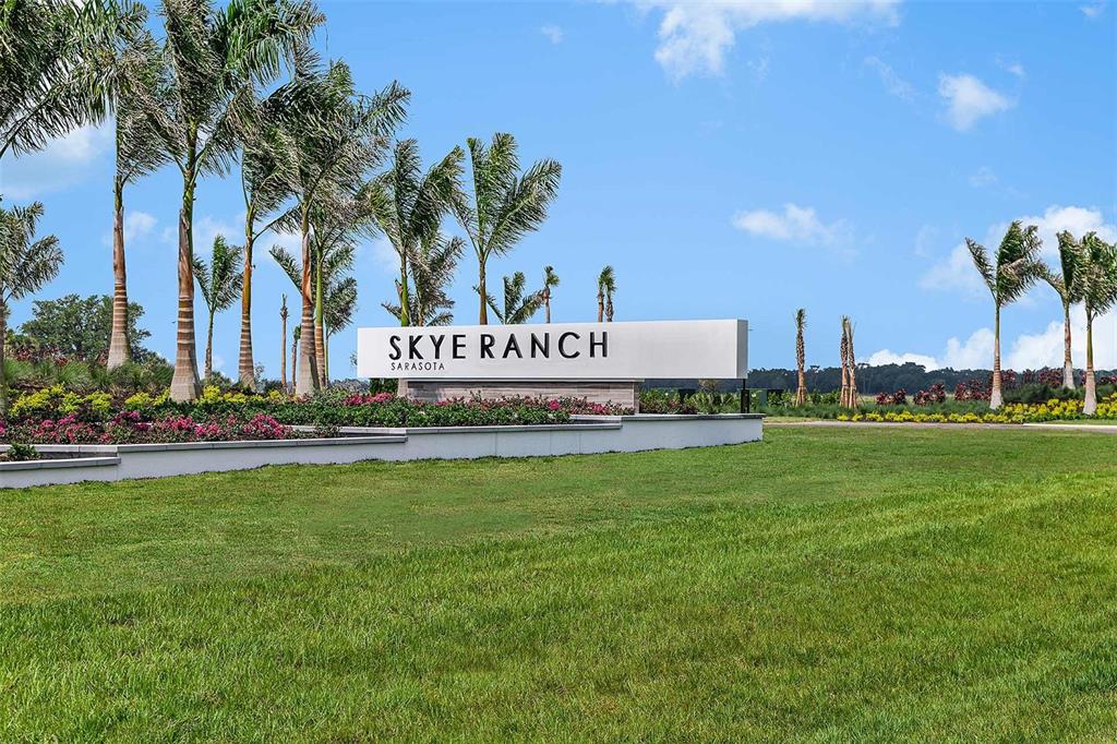 A white monument sign for Skye Ranch Sarasota stands in a landscaped grassy area — 7824 CENTAURUS WAY, SARASOTA, FL