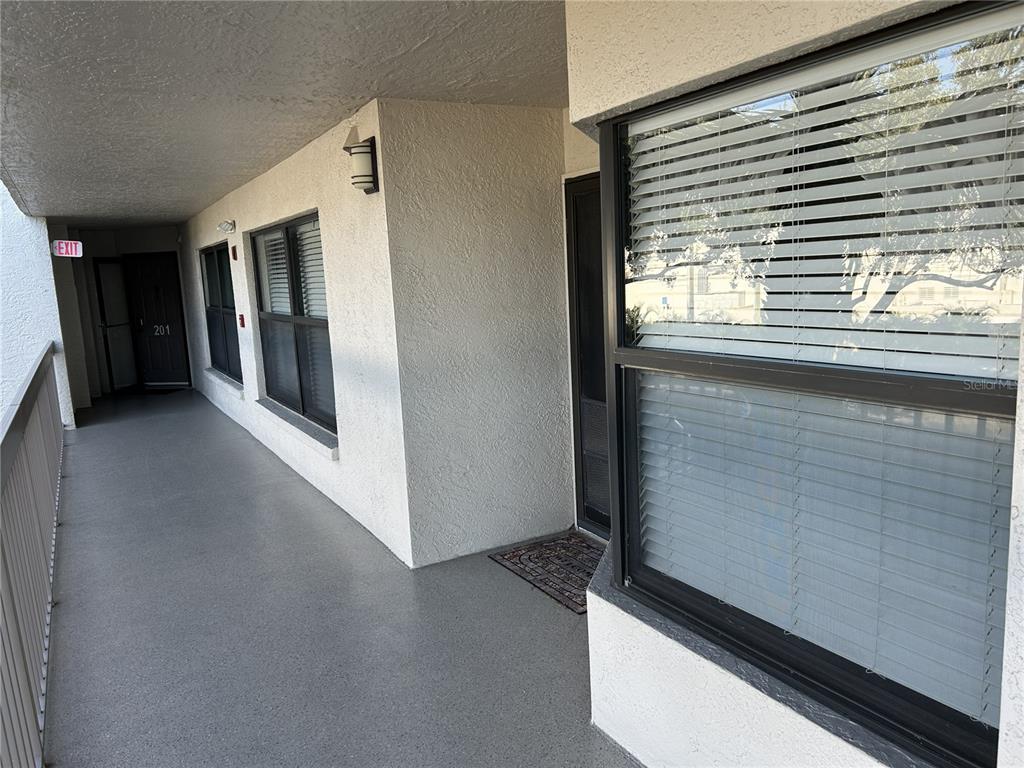 An exterior walkway leads to the entrance of a residential unit with a window — 1316 PASADENA AVENUE S UNIT 202, SOUTH PASADENA, FL