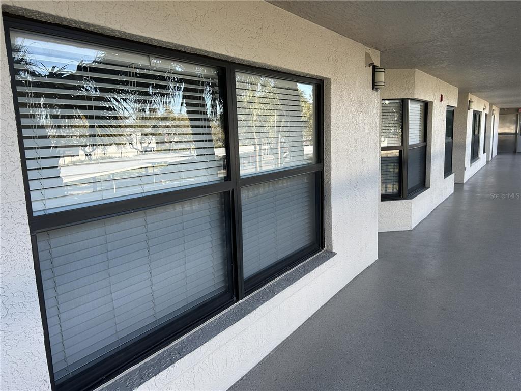 A view of a building exterior with dark-framed windows and a covered walkway — 1316 PASADENA AVENUE S UNIT 202, SOUTH PASADENA, FL