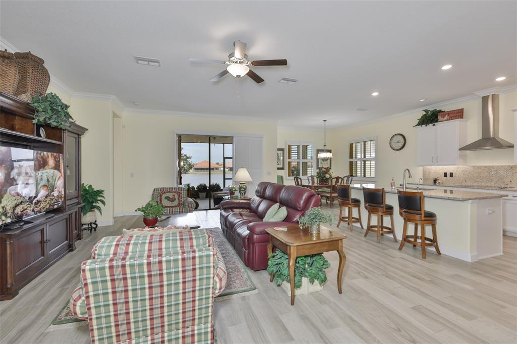 An open-concept living room and kitchen feature light wood flooring, a red sofa, and island seating — 16955 SCUBA CREST STREET, WIMAUMA, FL