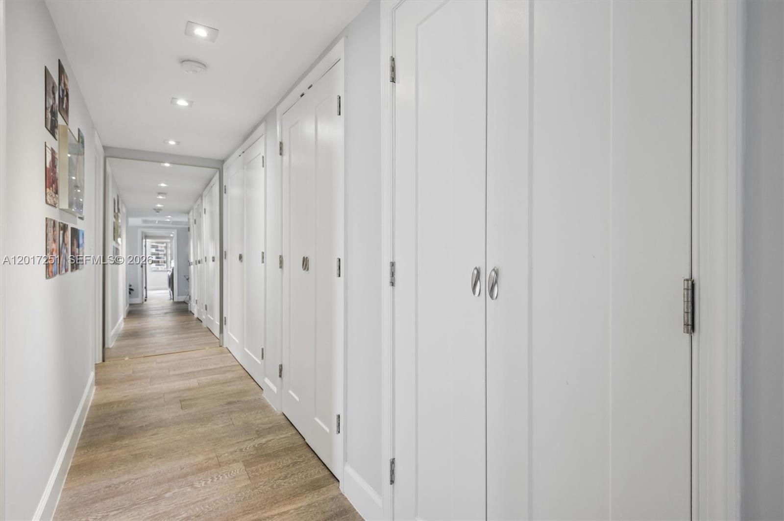 A long hallway features white paneled doors, recessed lighting, and light-colored wood flooring — 5660 Collins Ave # 6C, Miami Beach FL 33140, MIAMI BEACH, FL