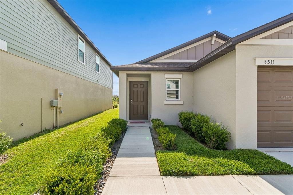 A concrete walkway leads to the front entrance of a house with a garage — 3511 GREAT PARK CT, PLANT CITY, FL