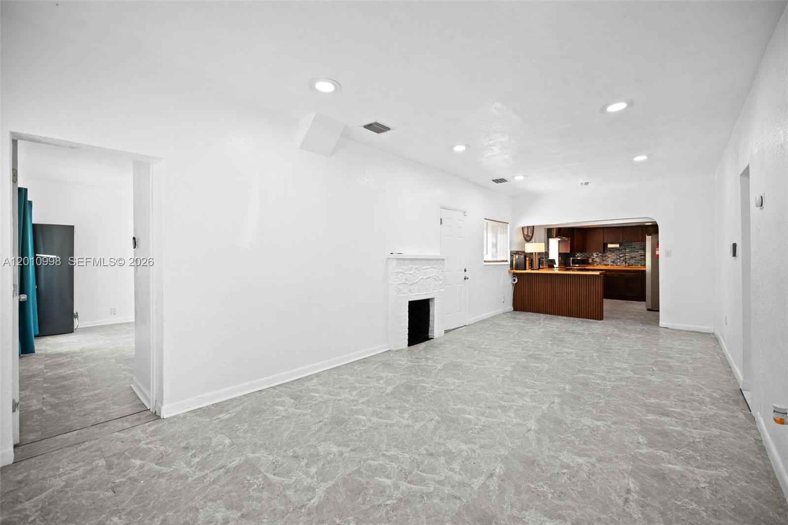A living room with gray tile flooring, a white fireplace, and an open kitchen — 1199 NW 121st St, North Miami FL 33168, NORTH MIAMI, FL