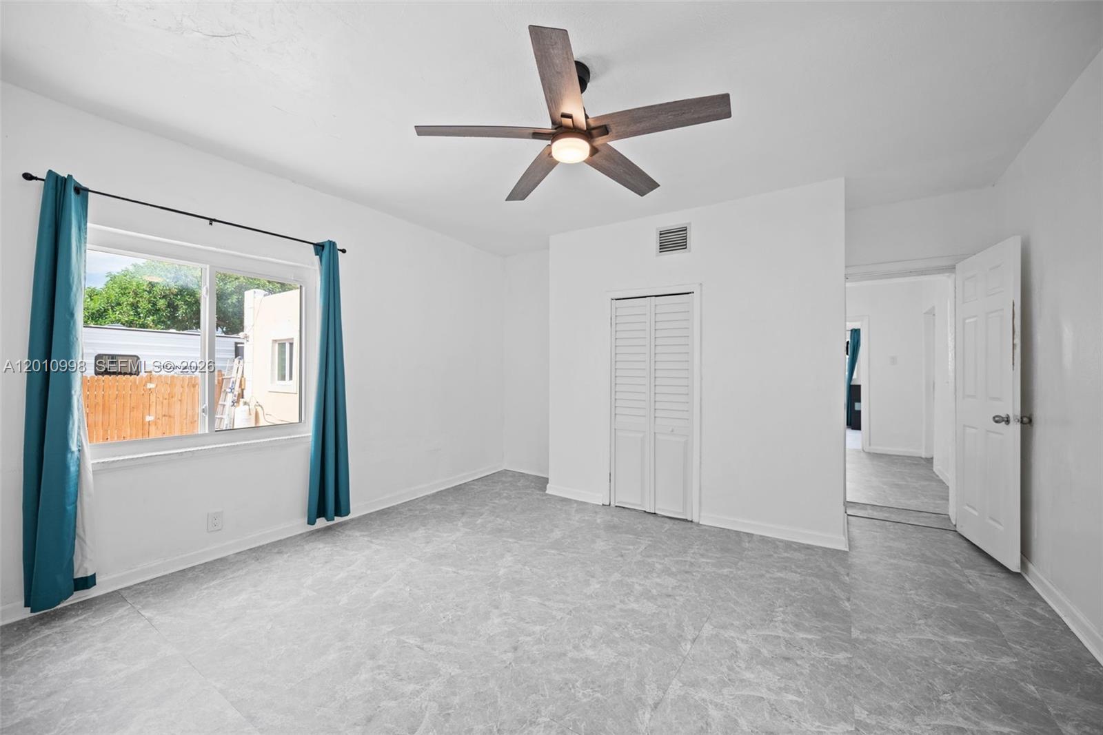 A bedroom features white walls, gray marble-look tile flooring, a ceiling fan, and a closet — 1199 NW 121st St, North Miami FL 33168, NORTH MIAMI, FL