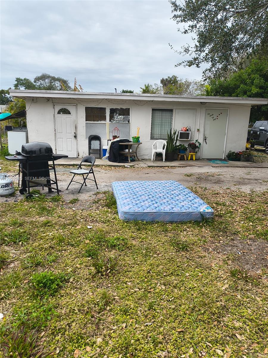 The exterior of a single-story house features a concrete patio, a grill, and a mattress — 5718 Mckinley St, Hollywood FL 33021, HOLLYWOOD, FL