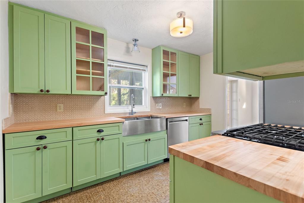 A kitchen features light green cabinets, butcher block countertops, a farmhouse sink, and stainless appliances — 437 RICHMOND STREET, ORLANDO, FL