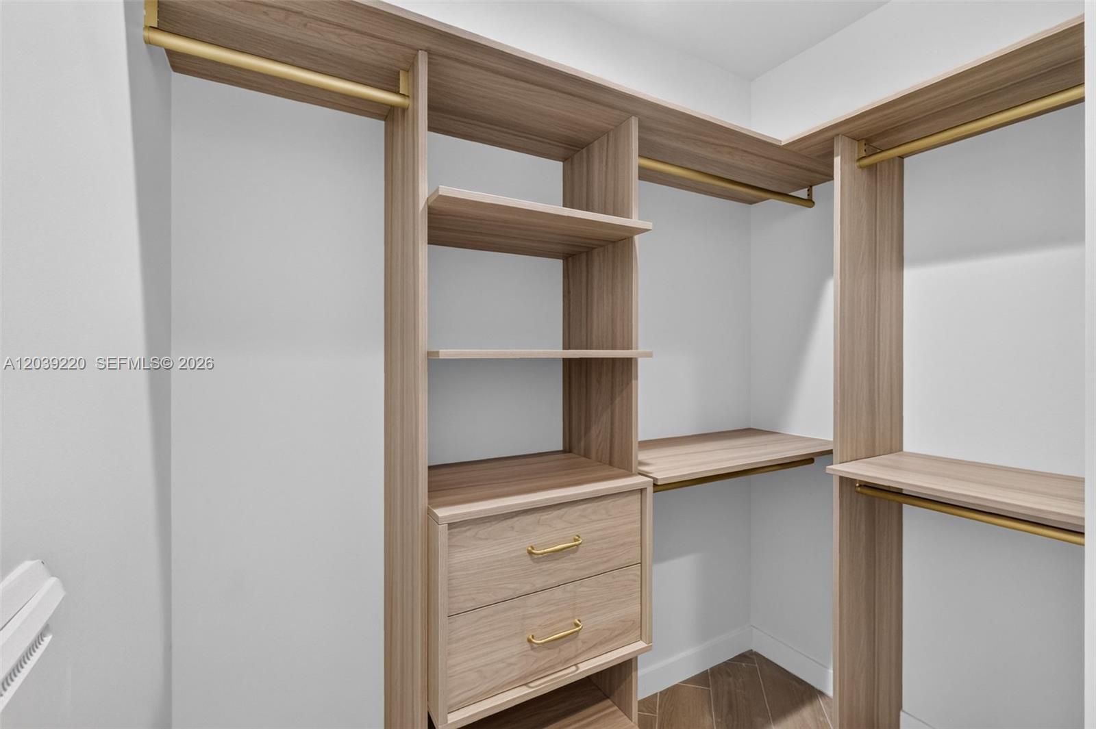 A walk-in closet features light wood shelving, hanging rods, and two drawers with gold hardware — 2700 NW 2ND AVE # 528, Miami FL 33127, MIAMI, FL