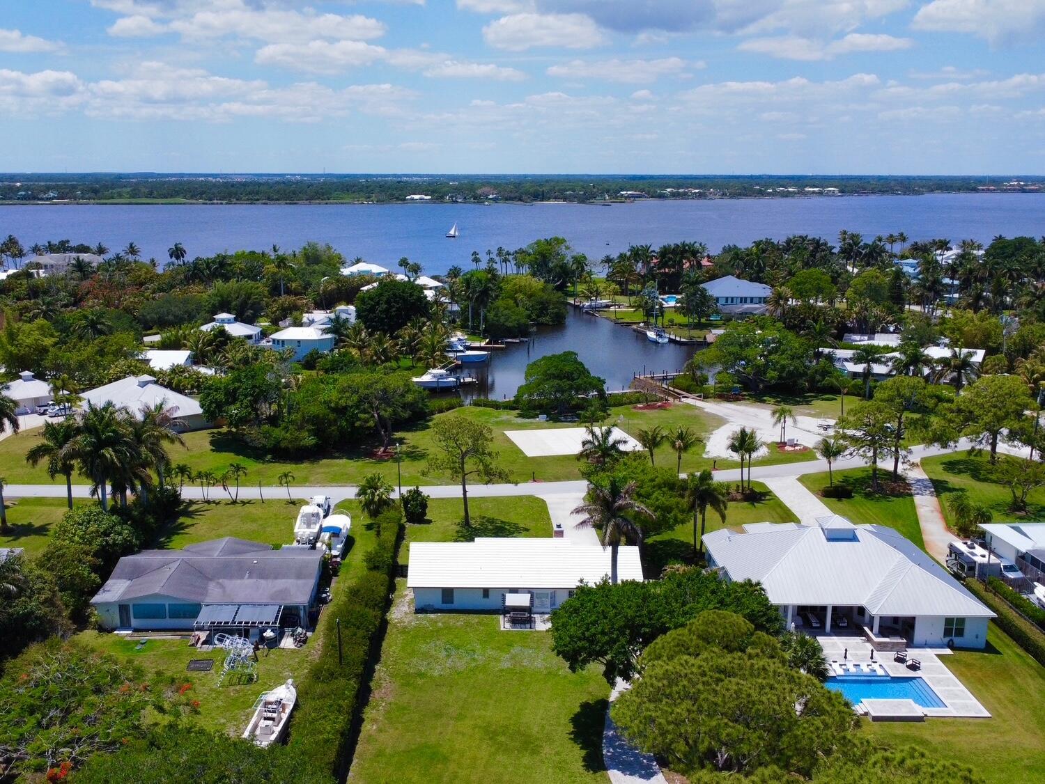An aerial view shows three houses with white roofs, a swimming pool, and a canal — 1655 NW Fork Road, Stuart FL 34994, STUART, FL