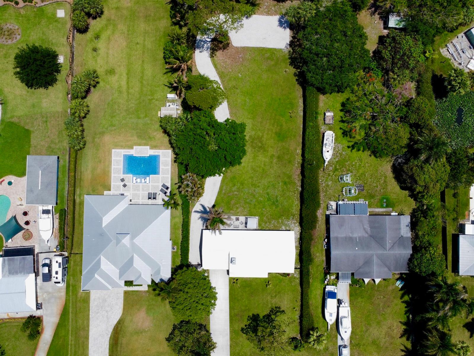 An aerial view shows three residential properties with swimming pools, driveways, and boats on lawns — 1655 NW Fork Road, Stuart FL 34994, STUART, FL